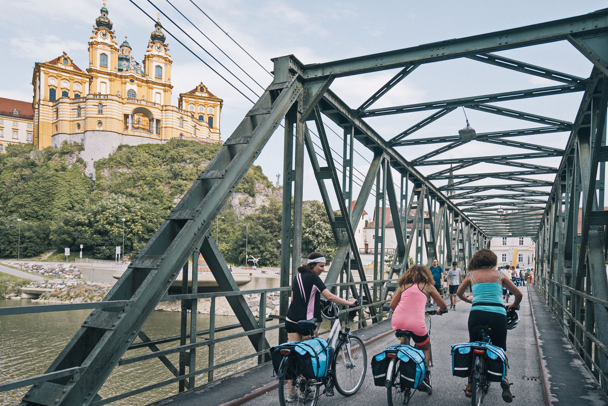 Gruppo di ciclisti in viaggio con "Girolibero" che attraversa un ponte di metallo lungo la ciclabile del Danubio
